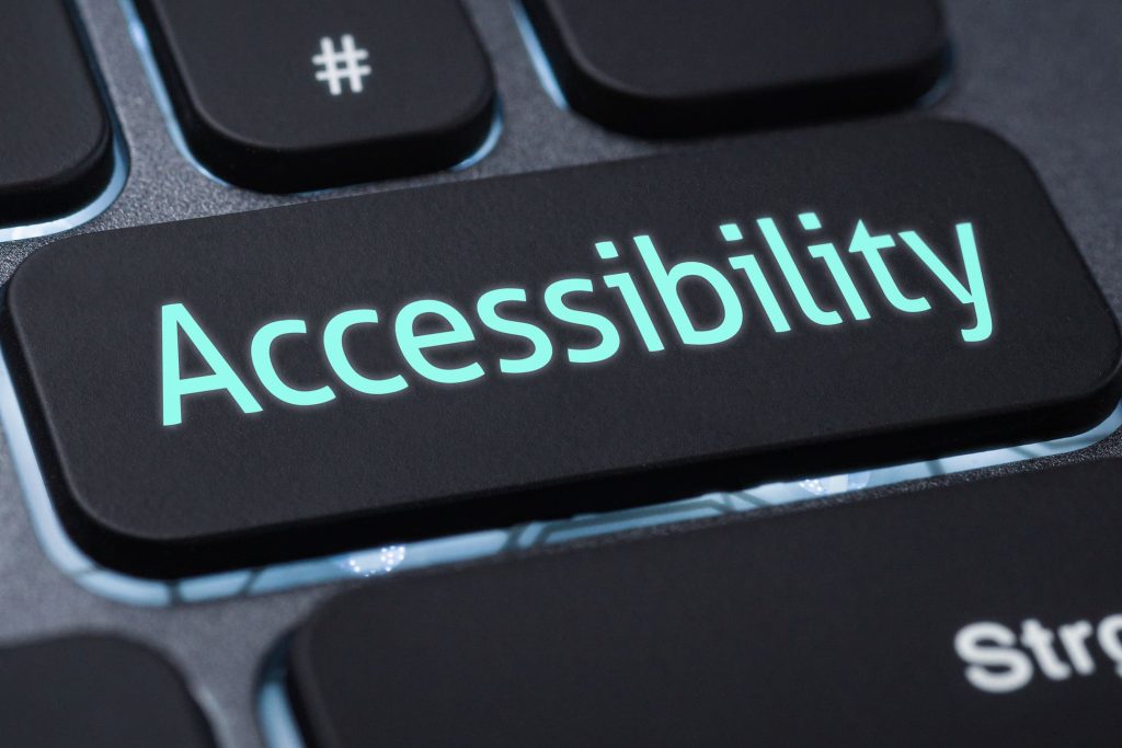 Close‑up of a black computer keyboard featuring a custom key labeled ‘Accessibility’ glowing in teal.